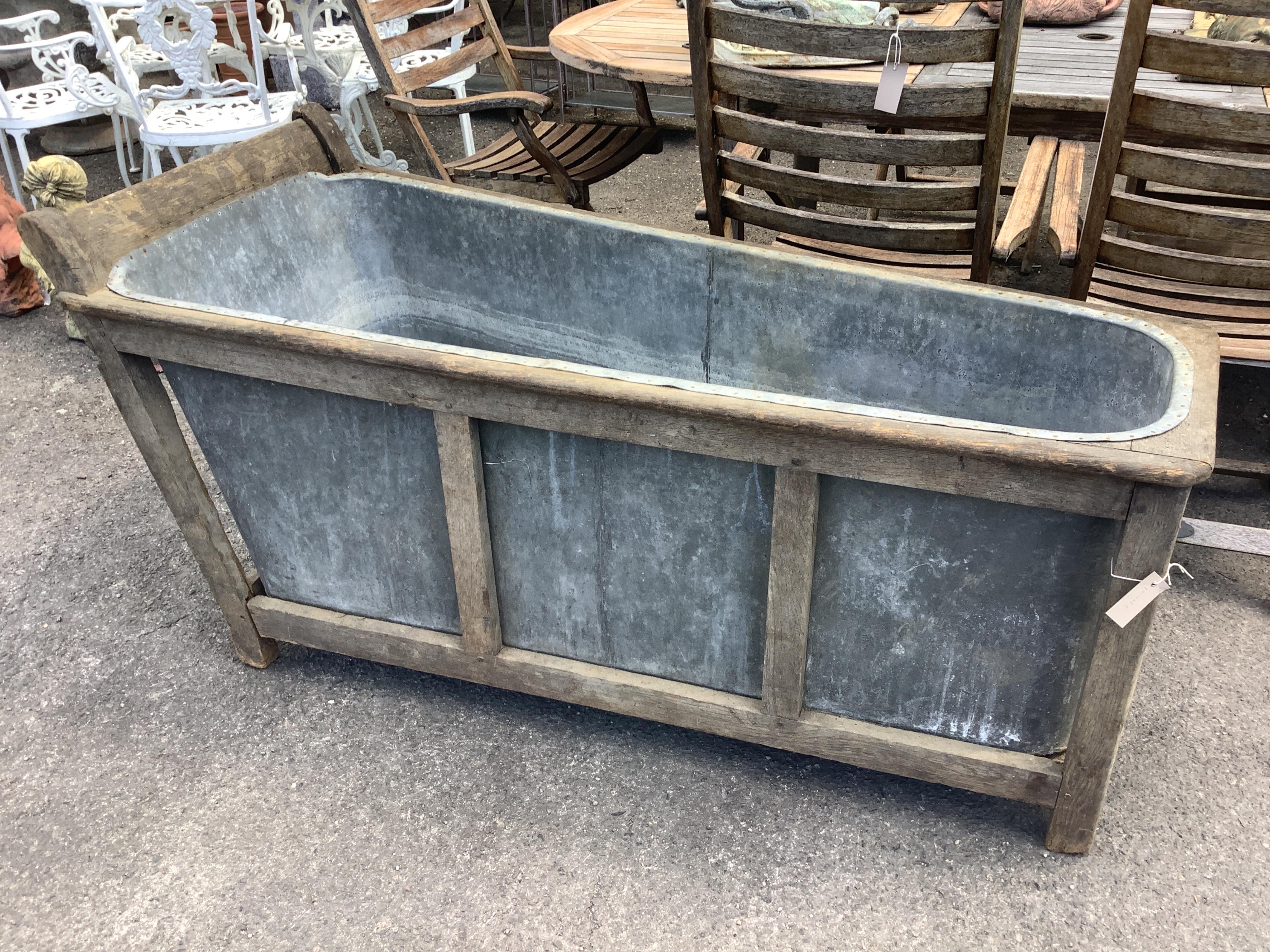 A 19th century French Provincial zinc lined bath with a wooden surround, length 153cm, height 74cm